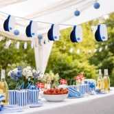 Studenterfest i haven med guirlande af blå studenterhuer, pyntet festbord med blå og hvide dekorationer, danske flag og jordbær.