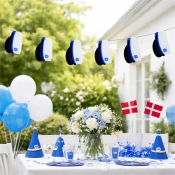 Studenterfest med guirlande af blå studenterhuer over pyntet festbord med blå og hvide dekorationer, blomster og danske flag.