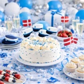 Studenterfest med pyntet kagebord og studenterkage dekoreret med mørkeblå kagetoppe