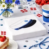 Blå studentservietter med studenterhue på opdækket bord til studenterfest med kage, jordbær, blomster og danske flag.